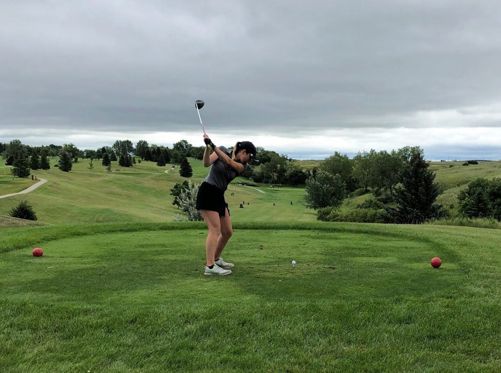 Girl teeing off at golf course